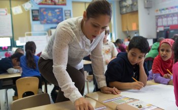 Kindergarten teacher helping students.
