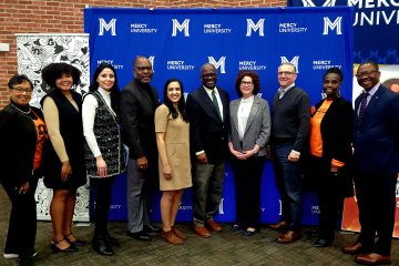 Mercy University, Westchester County government officials and Sister to Sister International pose in front of Mercy University step and repeat at MedTech & Finance Conference