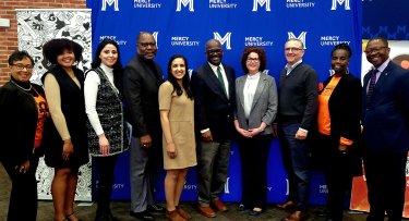 Mercy University, Westchester County government officials and Sister to Sister International pose in front of Mercy University step and repeat at MedTech & Finance Conference