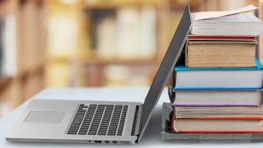 Laptop next to books.